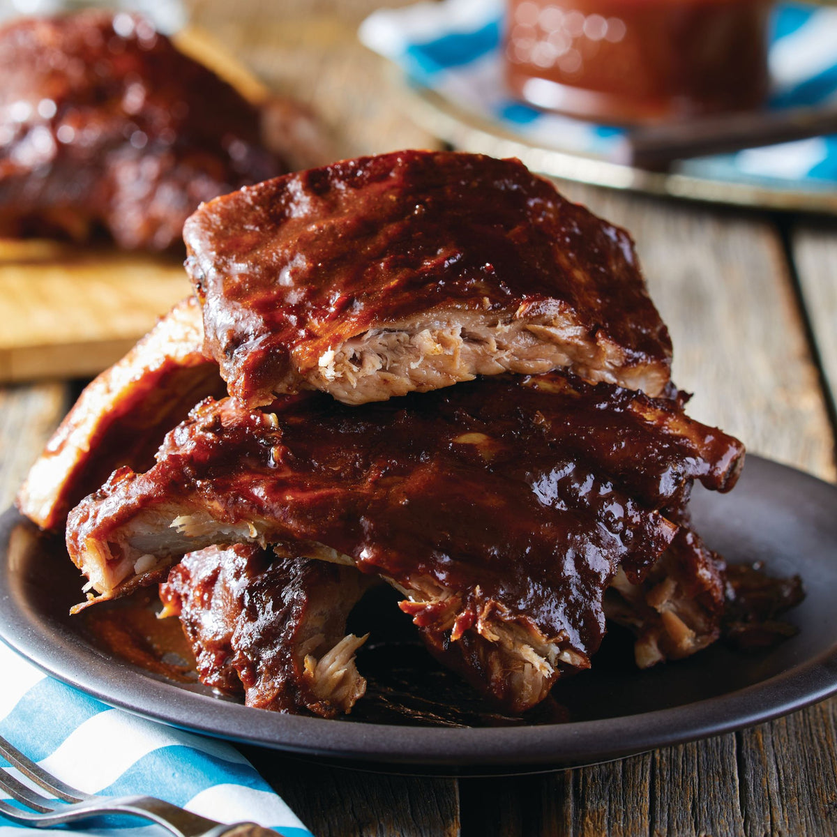 Pile de côtes levées nappées de sauce barbecue sur une assiette sur une table en bois
