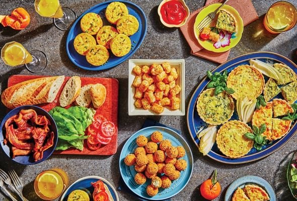 Assortiment d’aliments déjeuner incluant pain, légumes et pommes de terre rissolées sur une table