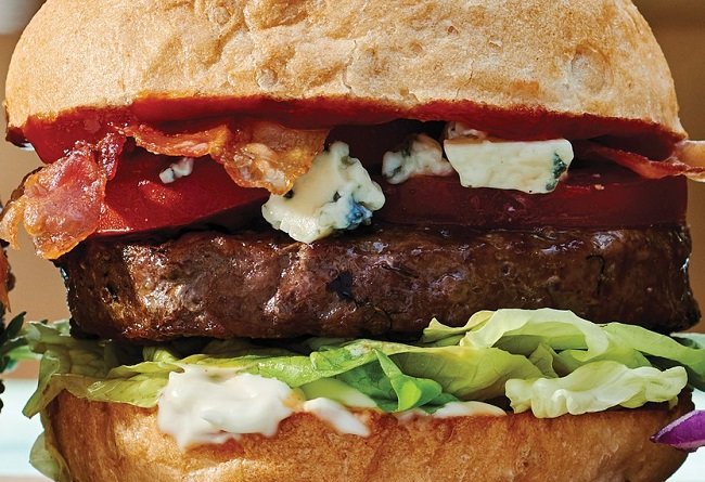 Gros plan d’un burger de bœuf avec bacon, fromage bleu et laitue dans un pain