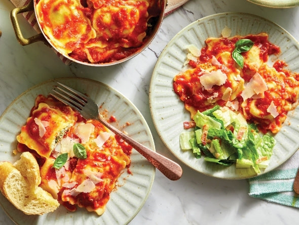 Deux assiettes de raviolis avec sauce tomate, fromage et basilic sur une surface en marbre