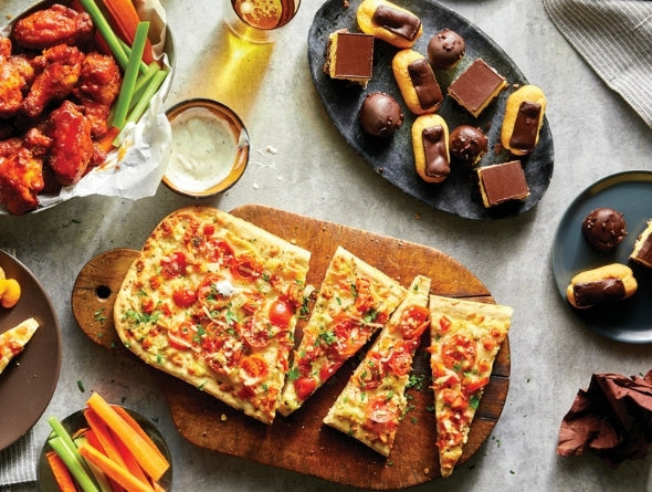Plats servis comprenant pizza, ailes et desserts sur une table